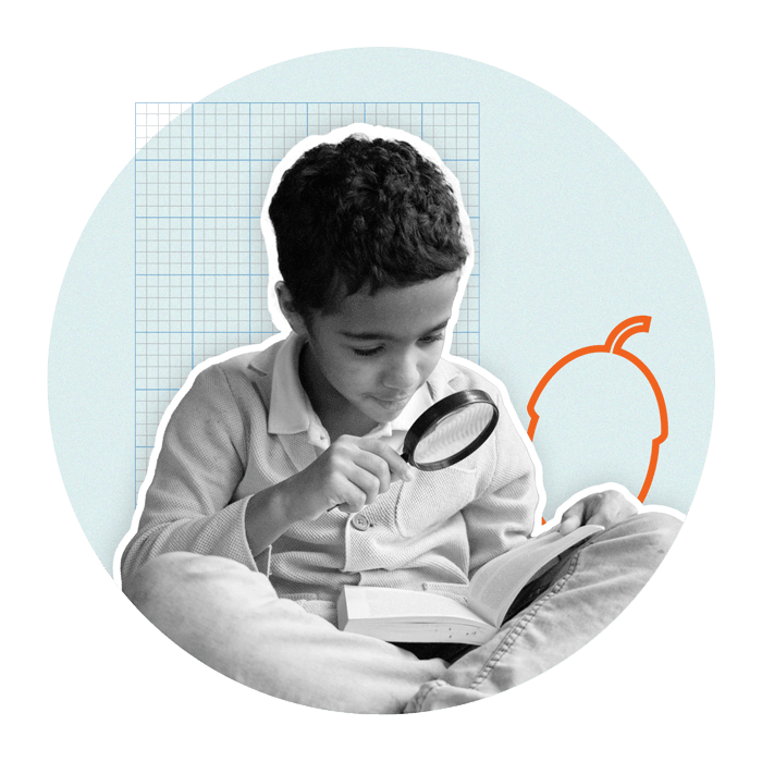 Boy holding magnifying glass over a book