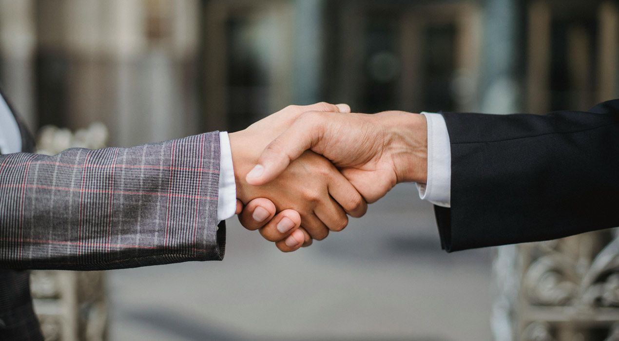 Close up photo of two people in suits shaking hands