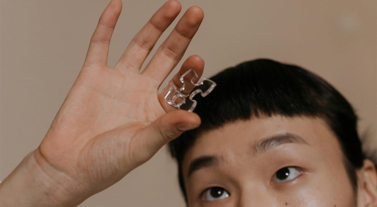 Close up of a young man holding a puzzle piece made from clear plastic up to the light
