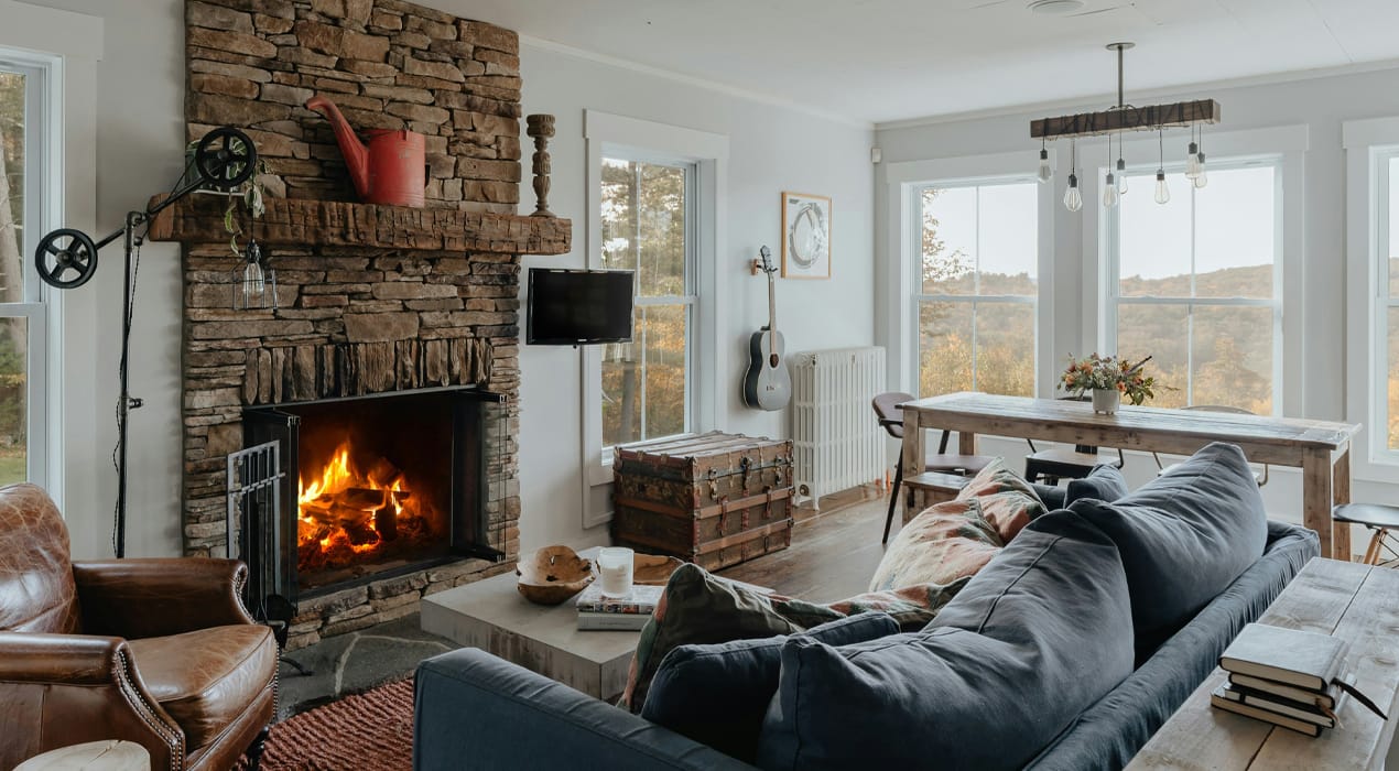 Picture of a cosy looking lounge, with a fire burning, and a view out over some hills