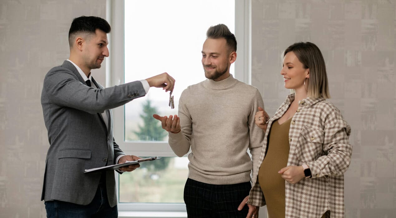 Real estate agent handing over new house keys to a young couple
