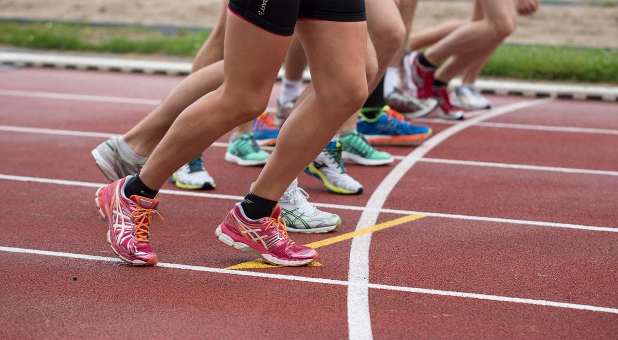 Runners on a race track, pictured from the waist down